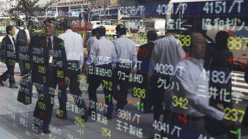 Pedestrians are reflected on the electronic stock board of a securities firm in Tokyo, Japan, Friday, Nov. 4, 2011.
