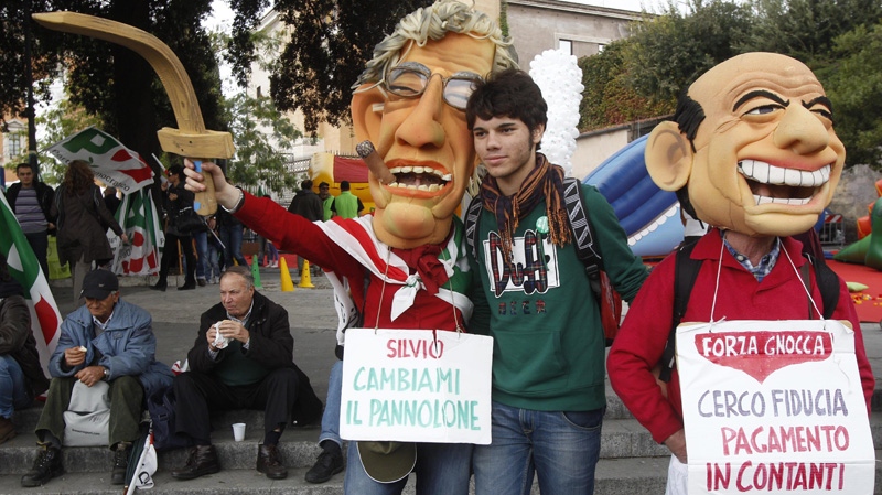 Demonstrators wear masks mocking Italian Premier Silvio Berlusconi, right, and Reform Minister Umberto Bossi carrying placards reading: "Silvio, change my diaper", left, and "I'm looking for confidence, payment in cash" during a demonstration staged by the Italian Democratic party in Rome, Saturday, Nov. 5, 2011. (AP Photo/Pier Paolo Cito)