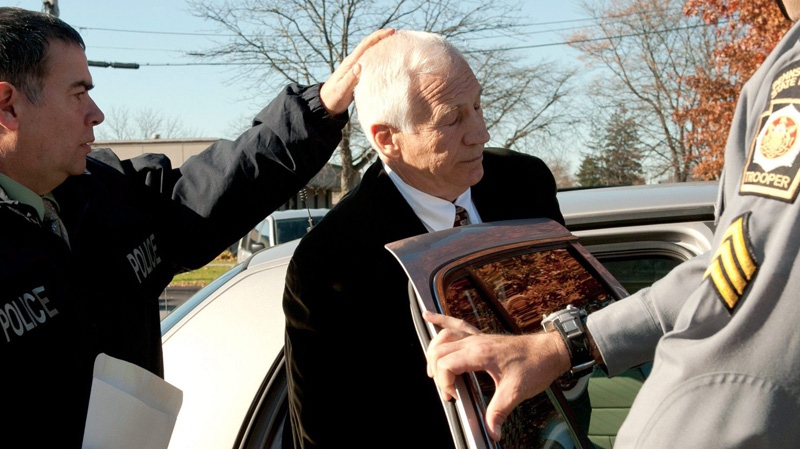 In this photo provided by the Pennsylvania Office of Attorney General, former Penn State football defensive coordinator Gerald "Jerry" Sandusky, centre, is placed in a police car in Bellefonte, Pa. to be taken to the office of a Centre County Magisterial District judge on Saturday, Nov. 5, 2011. (AP Photo/Pennsylvania Office of Attorney General, Commonwealth Media Services)