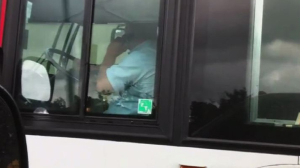 A bus driver is seen talking on a cellphone while driving in this image taken from YouTube.