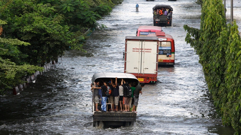 Thai residents hold on to a truck as they cross flooded streets at Mon Chit area in Bangkok, Thailand on Tuesday, Nov. 8, 2011. (AP / Aaron Favila)