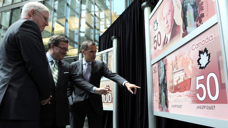 Bank of Canada Governor Mark Carney, right, Finance Minister Jim Flaherty, centre, and RCMP Commissioner William Elliott unveil the new polymer bank notes in $50 and $100 denominations at the Bank of Canada in Ottawa on Monday, June 20, 2011. (Sean Kilpatrick / THE CANADIAN PRESS)
