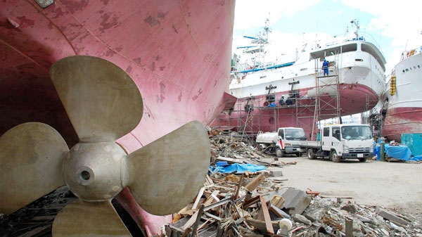 A ships washed ashore by the March 11 tsunami sits with red belly and a propeller exposed among debris of demolished houses in Kesennuma, Miyagi Prefecture, northeastern Japan on June 15, 2011. (AP / Malcolm Foster)