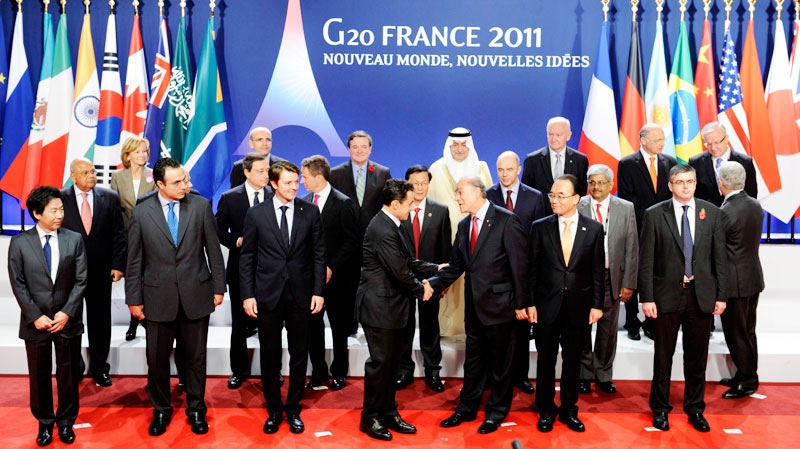 Secretary General of the Organisation for Economic Co-operation and Development, OECD, Jose Angel Gurria, third right, shakes hands with French President Nicolas Sarkozy as French finance minister Francois Baroin, third left, looks on, during a group photo Friday Nov. 4, 2011 at the G20 Summit in Cannes. (AP / Lionel Bonaventure, Pool)