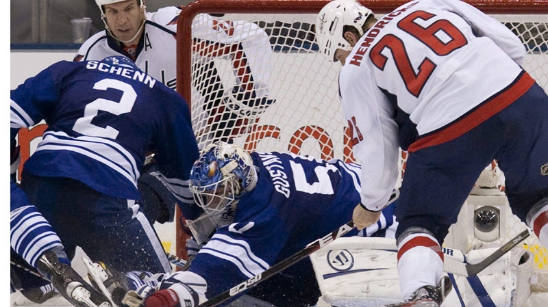 Toronto Maple Leafs goaltender Jonas Gustavsson (centre) reaches down to make a save under pressure from Washington Capitals' Matt Hendricks (right) during second period NHL hockey action in Toronto on Saturday November 19, 2011.THE CANADIAN PRESS/Chris Young