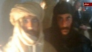 In this image from Libyan Television, Seif al-Islam Gadhafi, left, is guarded by a Libyan fighter as he is transported to Zintan, Libya, by a transport aircraft following his capture near the Niger border early Saturday Nov 19 2011. (AP Photo/ Libyan Television via APTN)