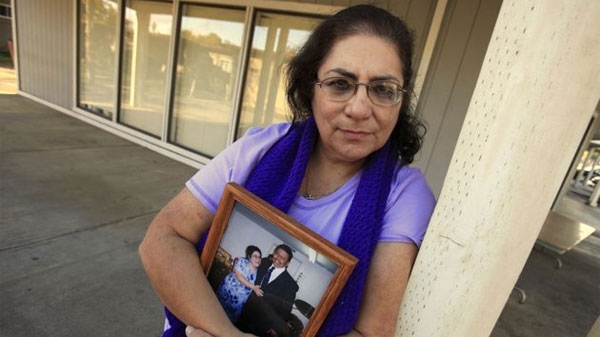 In this photo taken Nov. 4, 2011, Karen Carrisosa is seen with a photo of her and her husband Larry, at the site where he was killed in Sacramento, Calif. Carrisosa became concerned when officials found a Facebook posting from Corcoran State Prison inmate Fredrick Garner who is serving a 22-year, involuntary manslaughter sentence for killing Larry 11 years ago.