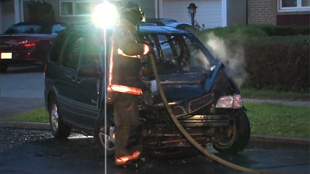 A firefighter hoses down a vehicle that burst into flames after hitting a pole in North York Friday, May 23, 2014. 