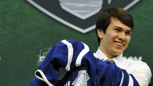 Stuart Percy puts on a jersey after being drafted in the first round by the Toronto Maple Leafs in the National Hockey League entry draft, Friday, June 24, 2011, in St. Paul, Minn. (AP Photo/Jim Mone)