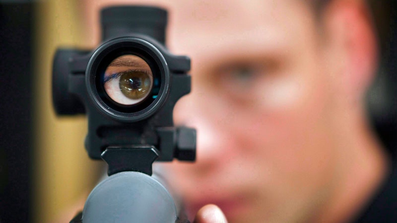 Patrick Deegan, a senior range officer at the Shooting Edge, looks through the scope of long gun at the store in Calgary, Sept. 15, 2010. (Jeff McIntosh / THE CANADIAN PRESS)