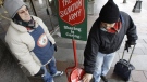 In this Dec. 17, 2008 file photo, Donald Baca, right, drops money into a Salvation Army red kettle as bell ringer Mark Pearson looks on in downtown Seattle. (AP Photo)