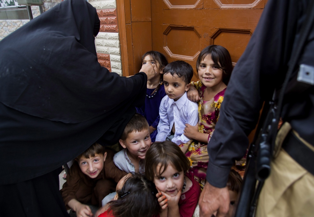 Pakistani children wait to receive polio vaccine