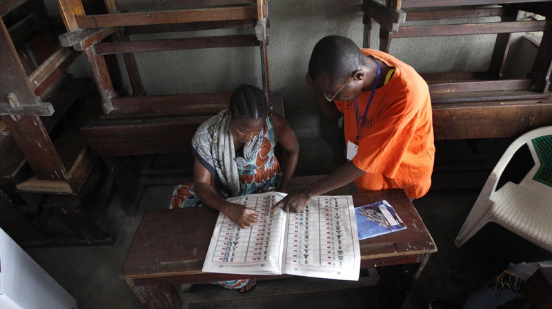 A woman who cannot read is given assistance by an election witness as she prepares to fill out a ballot in Kinshasa, Democratic Republic of Congo, on Nov. 28, 2011 