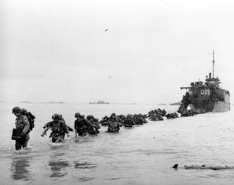 U.S. reinforcements wade through the surf from a landing craft in the days following D-Day and the Allied invasion of Nazi-occupied France at Normandy during World War II in June 1944. (AP / Bert Brandt)