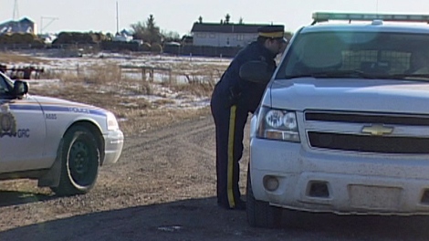 RCMP are seen near a rural property where two men were found dead near Earl Grey on Sunday in this photo taken Monday.