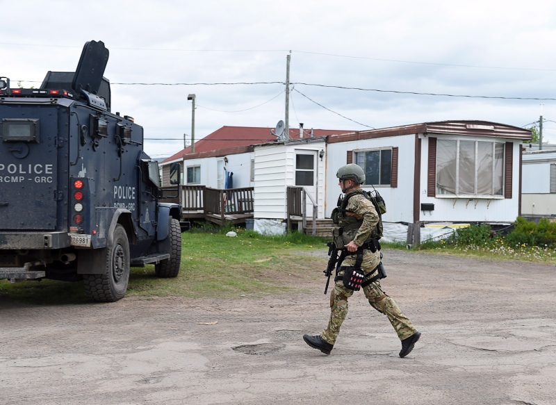An emergency response team member runs past a trailer where murder suspect 24-year-old Justin Bourque resides in Moncton, N.B. on Thursday, June 5, 2014. (Andrew Vaughan / THE CANADIAN PRESS)