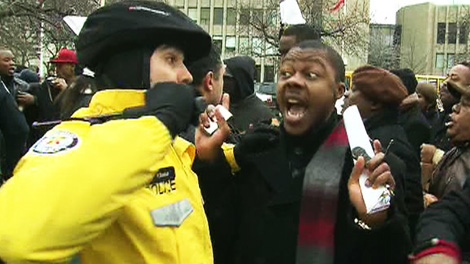 A police officer scuffles with a protester outside the U.S. Consulate in Toronto on Tuesday, Dec. 6, 2011.