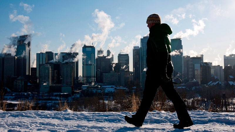 A man walks past a the Calgary, Alta., skyline during a deep freeze on Jan. 31, 2011. (Jeff McIntosh / THE CANADIAN PRESS)