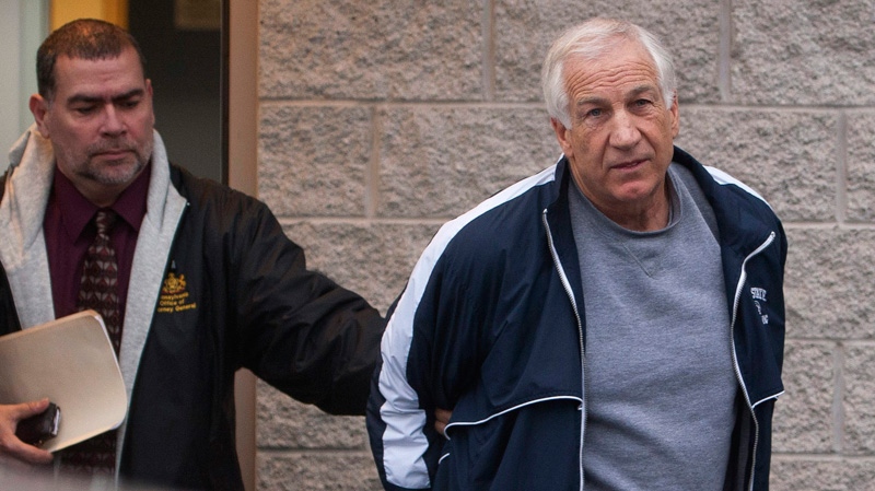 Former Penn State assistant football coach Jerry Sandusky, right, leaves the office of Centre County District Justice Daniel A. Hoffman under escort by Pennsylvania State Police and Attorney General's Office officials in Bellefonte, Pa., on Thursday, Dec. 7, 2011. (The Patriot-News / Andy Colwell)
