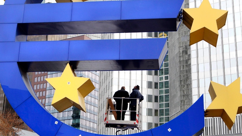 Workers change tube lights of the Euro sculpture in front of the European Central Bank in Frankfurt, Germany, Tuesday, Dec.6, 2011. (AP / Michael Probst)
