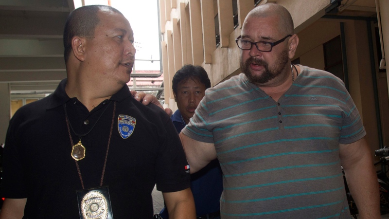 A Thai immigration officer escorts Russian mafia leader Alexander Matusov, right, as he leaves after a press conference at Immigration office in Bangkok, Thailand, Wednesday, June 25, 2014. (AP / Sakchai Lalit)