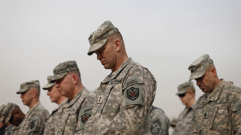 Military personnel lower their heads during ceremonies of the encasing of the US Forces Iraq colors, in Baghdad, Iraq, Thursday, Dec., 15, 2011.