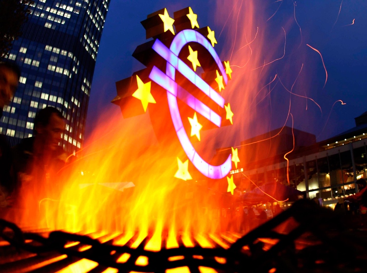 Activists of the Occupy Frankfurt movement set up a fire near a Euro sculpture last month. One of Canada's leading bank economists is predicting a year of slow economic growth, low interest rates and continued uncertainty due to the financial crisis underway in Europe. (AP / Michael Probst)