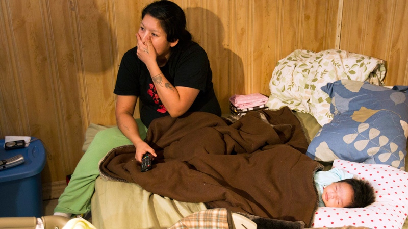 Lee Kamalatisit and her two-month-old daughter Kaylee sit in their unserviced, one-room home in Attawapiskat, Ont., Saturday, Dec. 17, 2011. (Frank Gunn / THE CANADIAN PRESS)