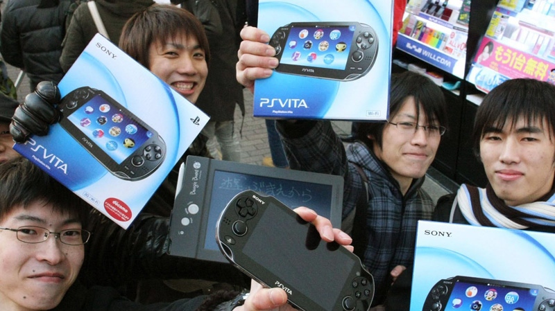 People show off their newly purchased PlayStation Vita portable games in Tokyo Saturday, Dec. 17, 2011. (AP Photo/Kyodo News)
