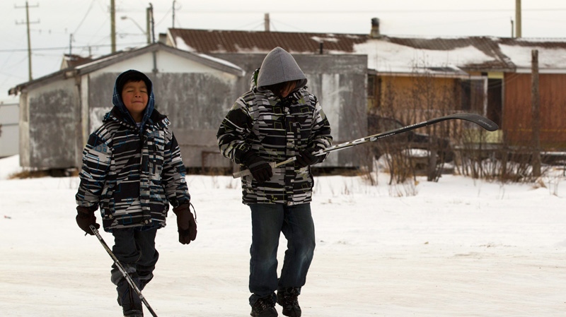 Two young boys walk past substandard housing on their way to play hockey in Attawapiskat, Ont. Saturday, Dec. 17, 2011. (Frank Gunn / THE CANADIAN PRESS)