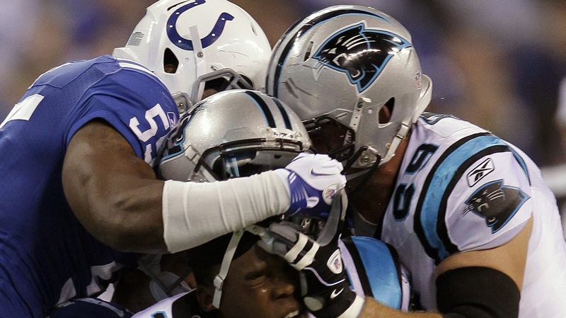 Carolina Panthers quarterback Cam Newton, center, loses his helmet as his tackled by Indianapolis Colts linebacker Ernie Sims, top, and middle linebacker Pat Angerer during the first quarter of an NFL football game in Indianapolis, Sunday, Nov. 27, 2011. (AP Photo/Darron Cummings)
