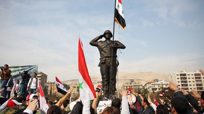 Pro-regime protesters gesture toward a statue of a solider during a rally at Umayyad Square in Damascus, Syria, Wednesday, Dec. 21, 2011. Syrian troops assaulting a northwest town. (AP / Bassem Tellawi)