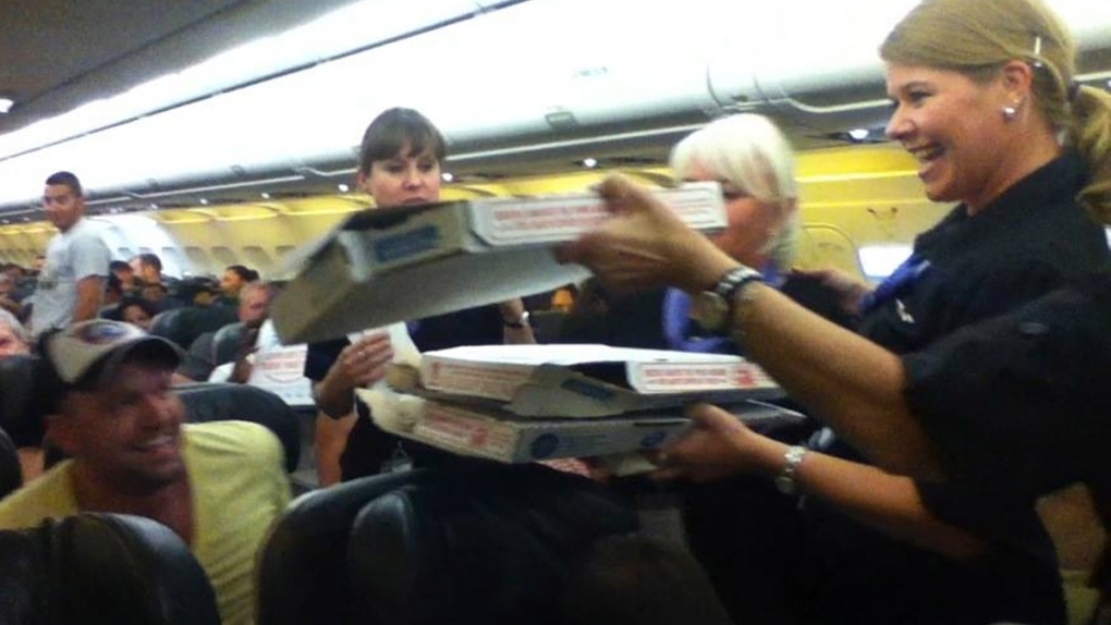 Frontier Airlines flight attendant hands out pizza