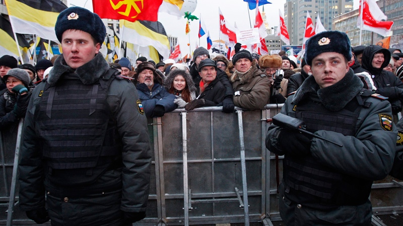 Russian police officers guard protesters during a rally against alleged vote rigging in Russia's parliamentary elections on Sakharov avenue in Moscow, Russia, Saturday, Dec. 24, 2011.