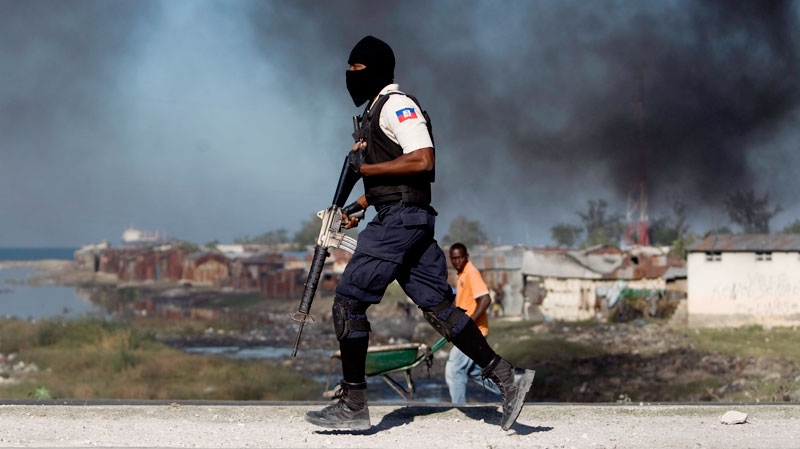 A police officer runs next to burning tires at the Cite Soleil slum in Port-au-Prince, Haiti, Saturday, Dec. 24,2011. (AP / Dieu Nalio Chery)