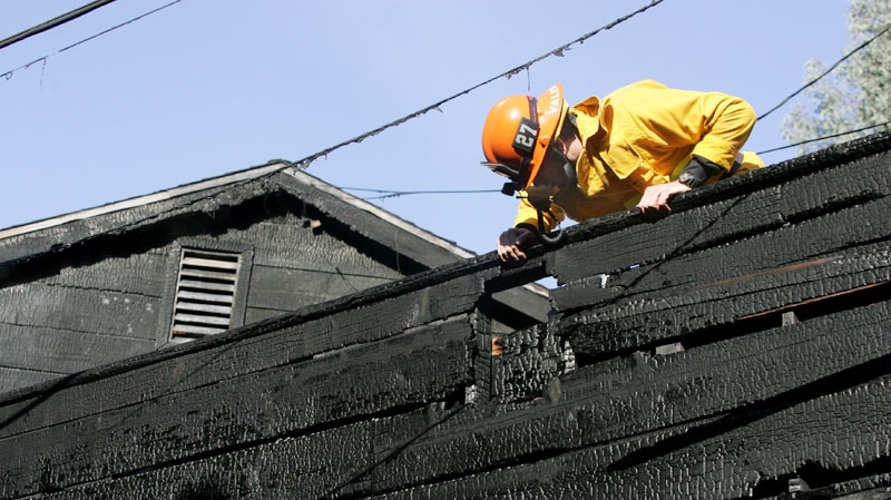 Los Angeles City firefighter Dane Jackson investigates the scene where fire caused damage to a home once occupied by Doors frontman Jim Morrison, at 8021 Rothdell Trail in the Hollywood Hills, section of Los Angeles, on Friday, Dec. 30, 2011. (AP / Ringo H.W. Chiu)