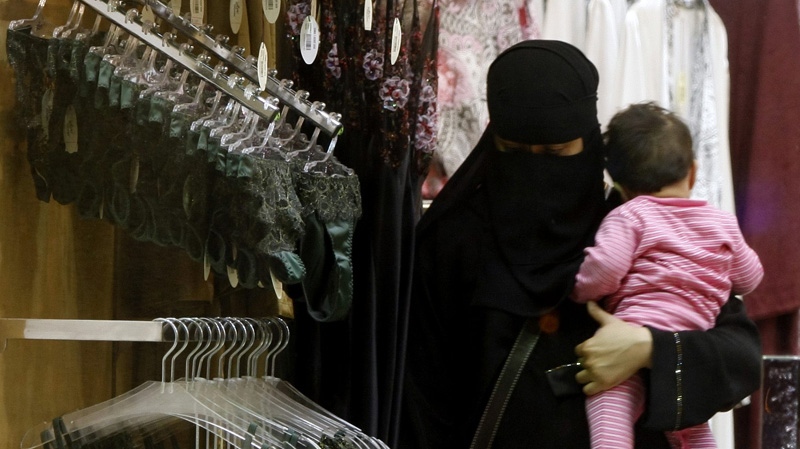 In this Wednesday, March 25, 2009 file photo, a Saudi woman holding a child checks out lingerie at a store in Riyadh, Saudi Arabia. (AP Photo/Hassan Ammar, File)
