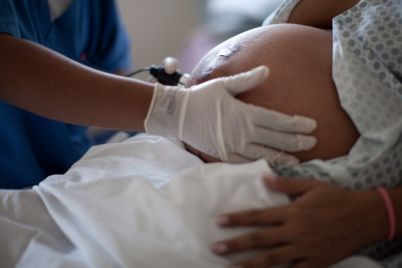 A pregnant woman is examined as she waits to give birth at a hospital on July 25, 2012. (Felipe Dana/AP)