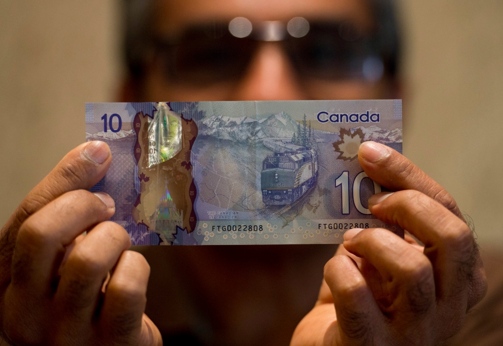 Hitesh Doshi poses with a $10 Canadian bank note