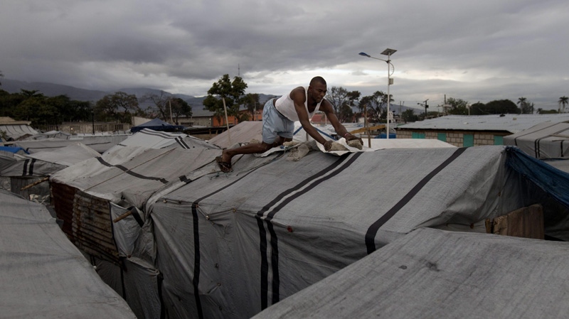 Pirist Dugard, 31, places rock on a tarp covering his tent at a camp set up for people displaced by the 2010 earthquake, in what used to be an airstrip in Port-au-Prince, Haiti, Jan. 4, 2012. (AP / Dieu Nalio Chery)
