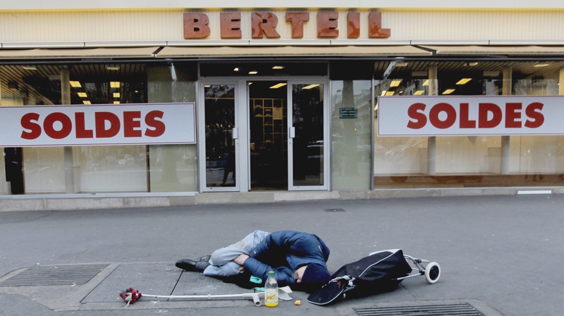A homeless man sleeps in front of a shop in Paris, France on Wednesday Jan. 11, 2012. (AP Photo/Jacques Brinon)