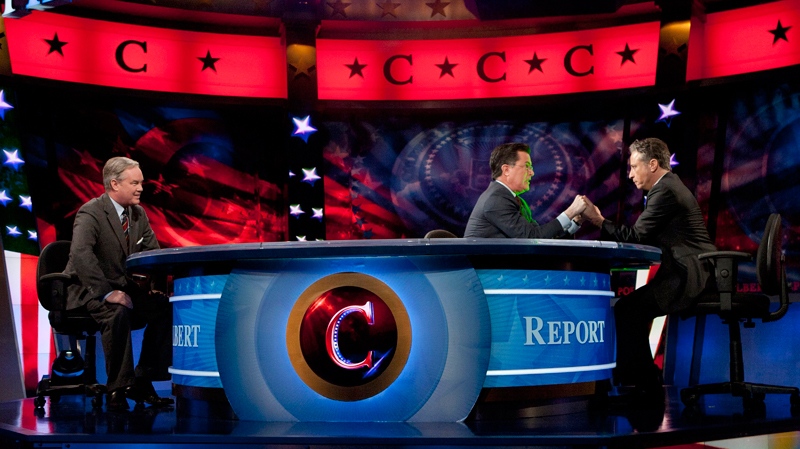 Stephen Colbert, centre, and John Stewart, right, hold hands during The Colbert Report, as Trevor Potter looks on Thursday, Jan. 12, 2012, in New York. 