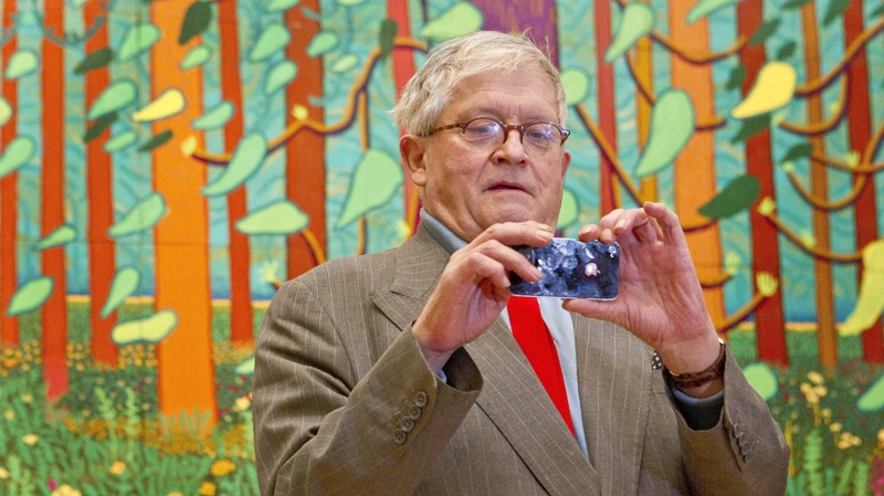 British artist David Hockney takes a photograph of the media as he stands before one of his paintings of the East Yorkshire landscape at The Royal Academy of Arts in Piccadilly, London, Monday, Jan. 16, 2012, ahead of his exhibition called 'A Bigger Picture'. (AP Photo/Joel Ryan)