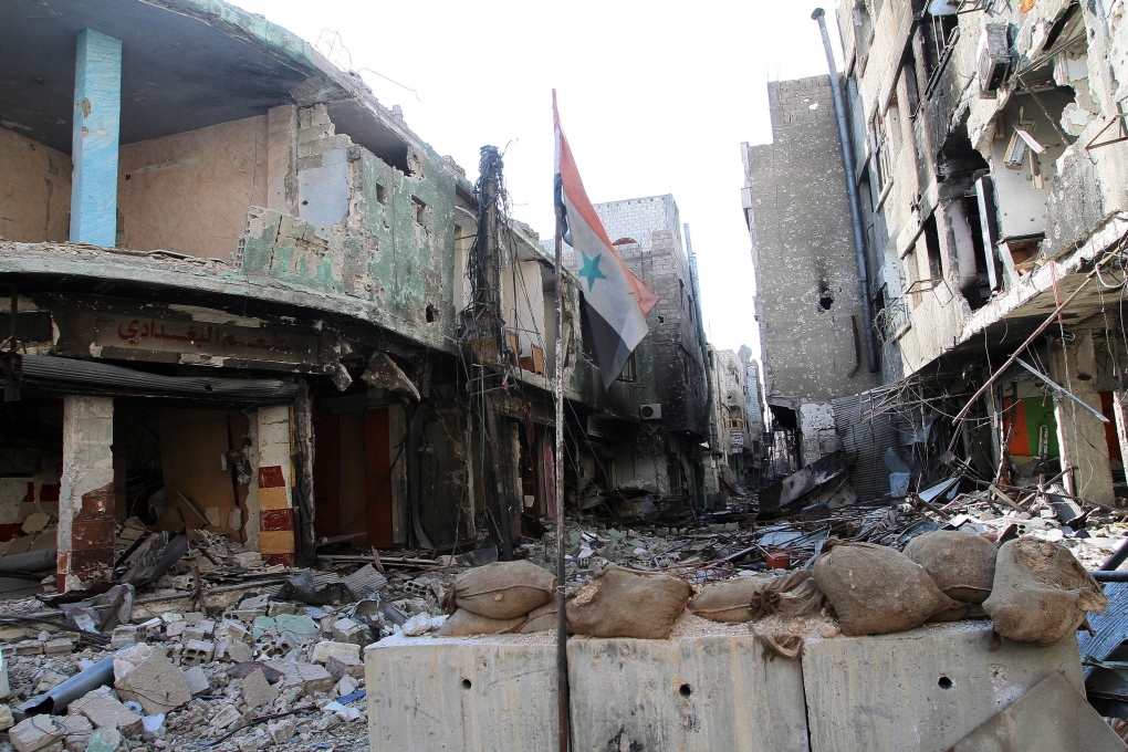 Syrian flag in rubble outside Damascus