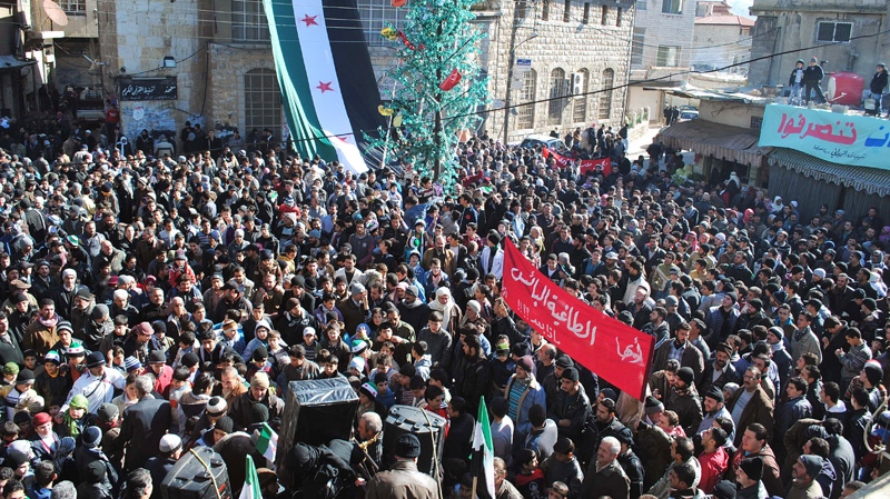 Anti-Syrian regime protesters gather at a square as they hold an Arabic banner, center, reading, "hey, the miserable, the tyrant, what else," during a demonstration at the mountain resort town of Zabadani, Syria, near the Lebanese border, on Friday Jan. 20, 2012. (AP Photo)