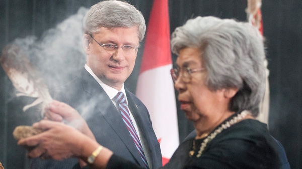 Prime Minister Stephen Harper looks on as Elder Commanda performs a smudging ceremony to open the Crown-First Nations Gathering in Ottawa, on Tuesday, Jan. 24, 2012. (Adrian Wyld / THE CANADIAN PRESS)