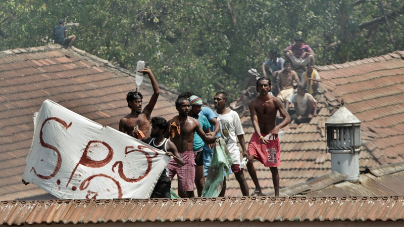 Sri Lankan prisoners climb onto neighboring buildings during a clash between prison guards and inmates in Colombo, Sri Lanka, Tuesday, Jan. 24, 2012. 