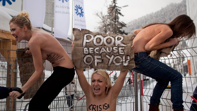 Topless Ukrainian protesters climb up a fence at the entrance to the congress center where the World Economic Forum takes place in Davos, Switzerland Saturday, Jan. 28, 2012.
