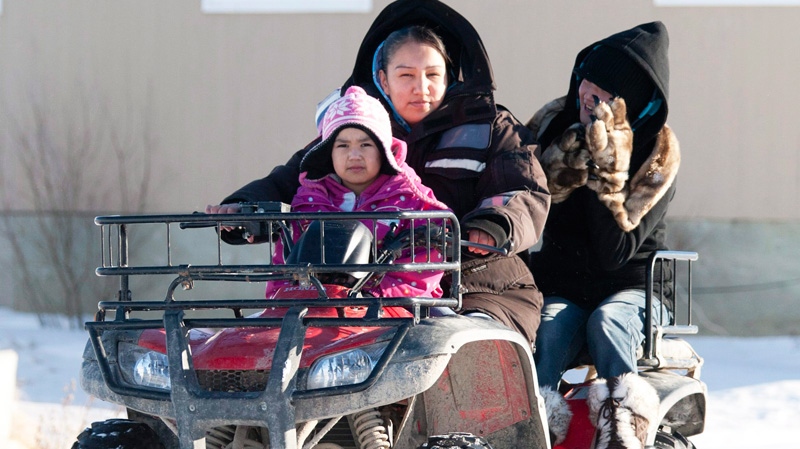 A woman takes children to school on a four wheel vehicle following their lunch break in Attawapiskat, Ont., Tuesday November 29, 2011.