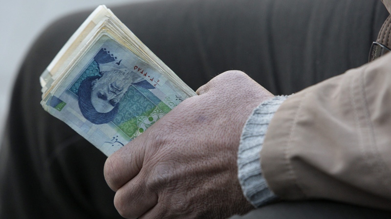 In this Jan. 26, 2012 file photo, an Iranian street money exchanger holds Iranian banknotes with a portrait of late revolutionary founder Ayatollah Khomeini, in the main old Bazaar of Tehran, Iran. (AP Photo/Vahid Salemi)